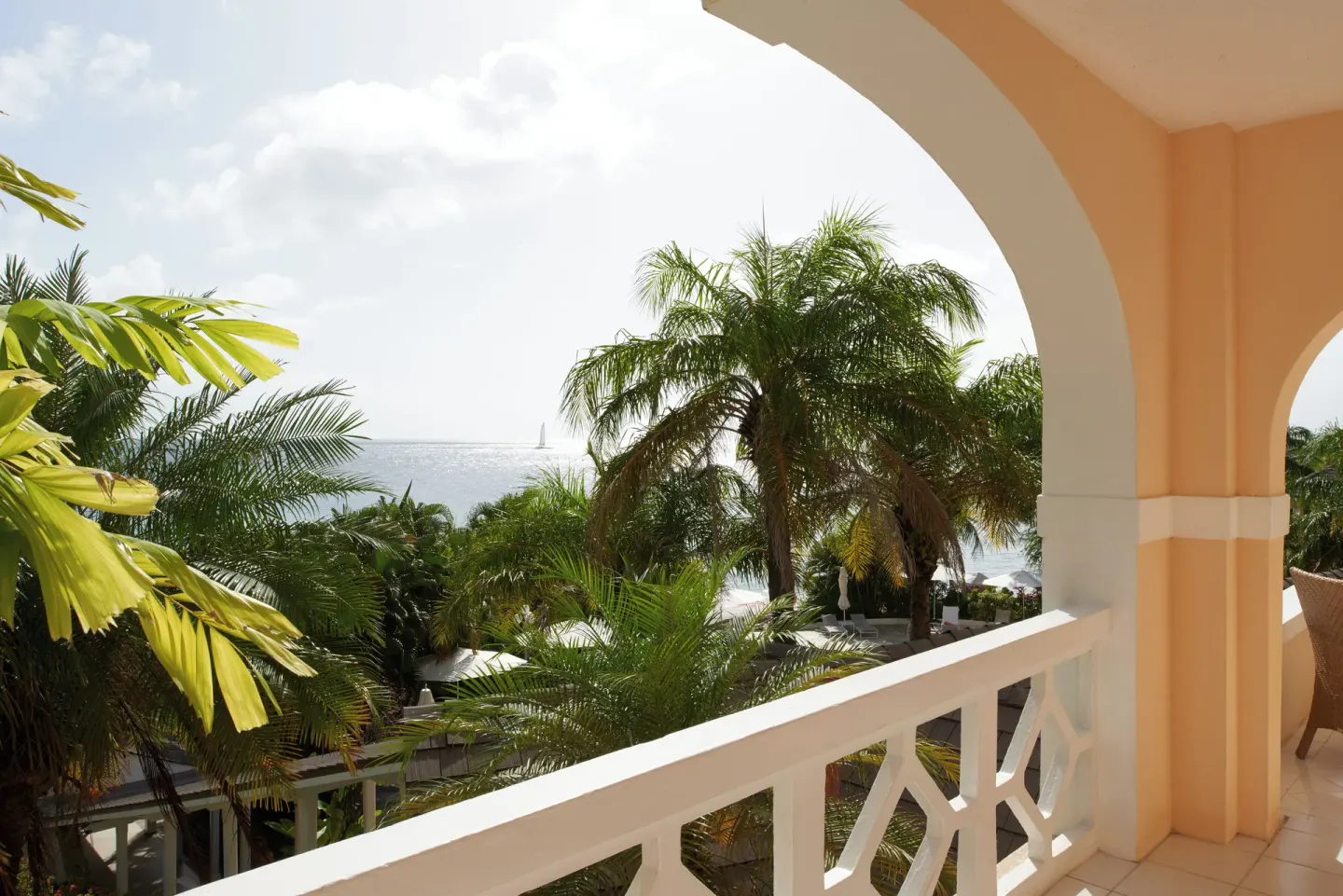 Balcony at BodyHoliday with arched opening, palms, and a distant ocean view.
