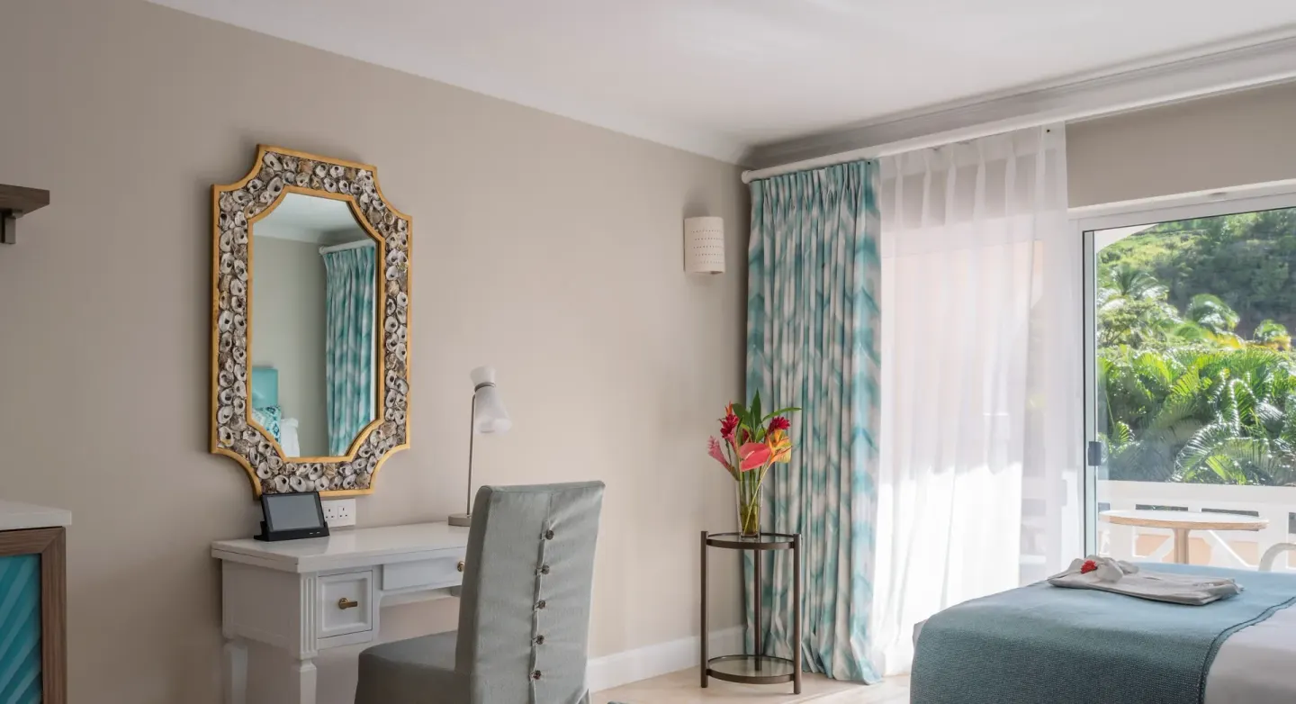 Garden View room at BodyHoliday with vanity desk, ornate mirror, bed, and balcony door.