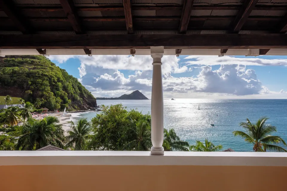 Ocean view from a covered balcony with bay, palms, and coastline at BodyHoliday.