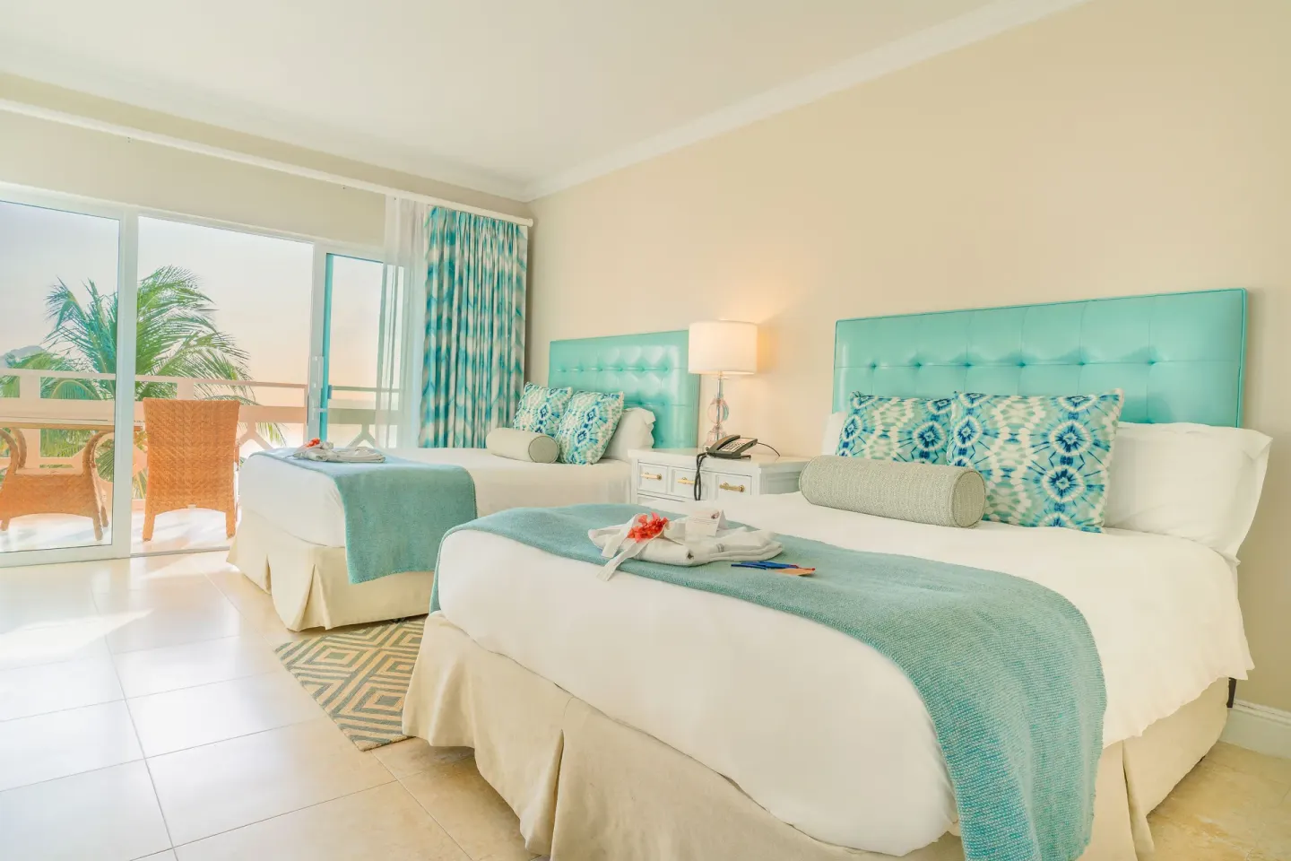 Ocean View Room with two beds, turquoise accents, and balcony seating at BodyHoliday.
