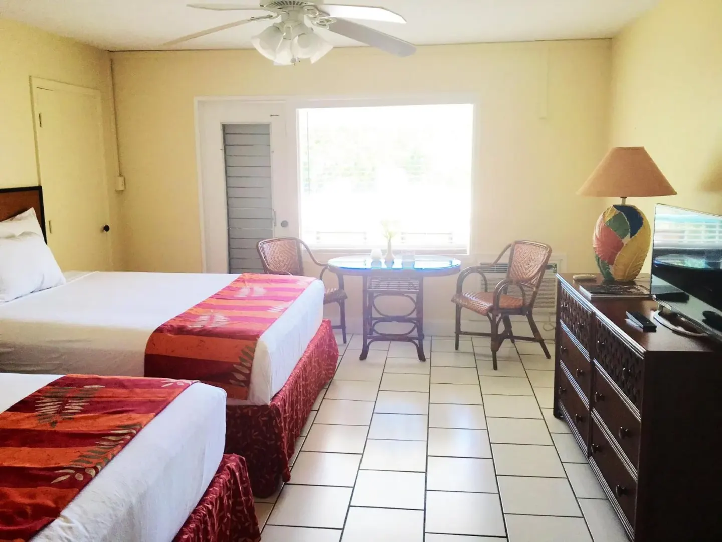 Guest room with two beds, wicker chairs and tile floor at Bolongo Bay Beach Resort.