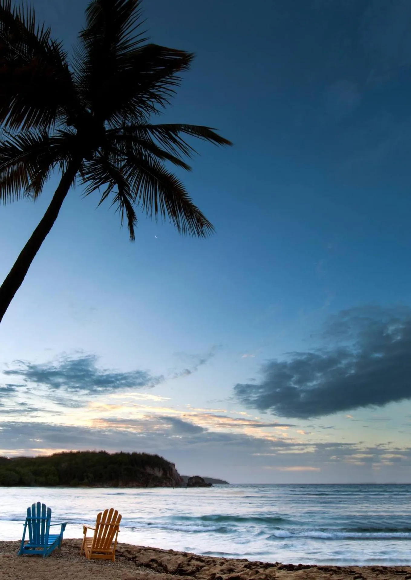 Beach chairs under a palm at sunset at Bolongo Bay Beach Resort.