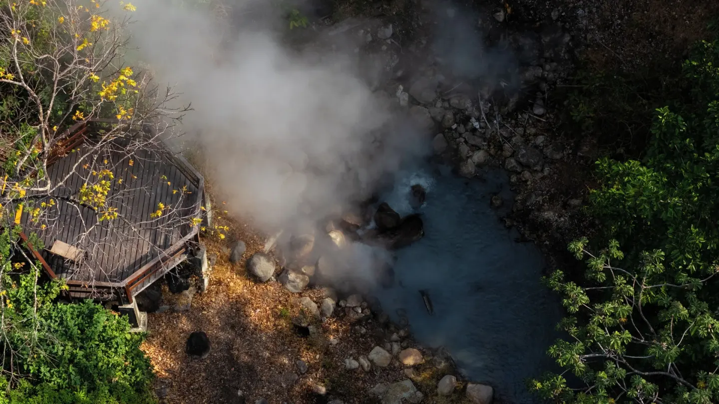 Aerial view of steam rising from a rocky thermal stream at Borinquen Thermal Resort.