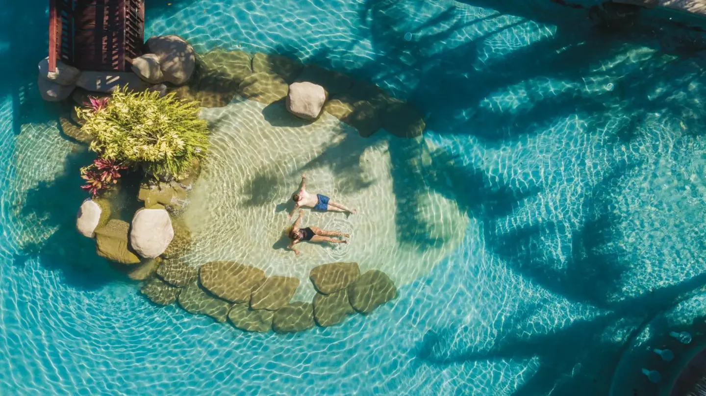 Aerial view of two guests floating in a clear pool at Borinquen Thermal Resort.