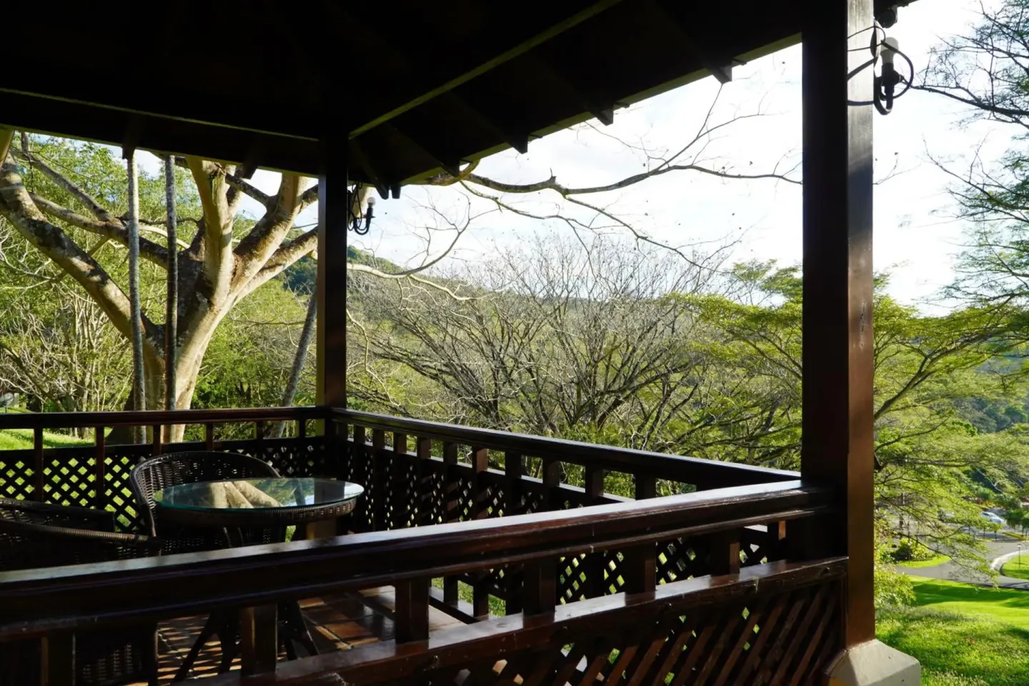 Covered balcony with a small table overlooking trees at Borinquen Thermal Resort.