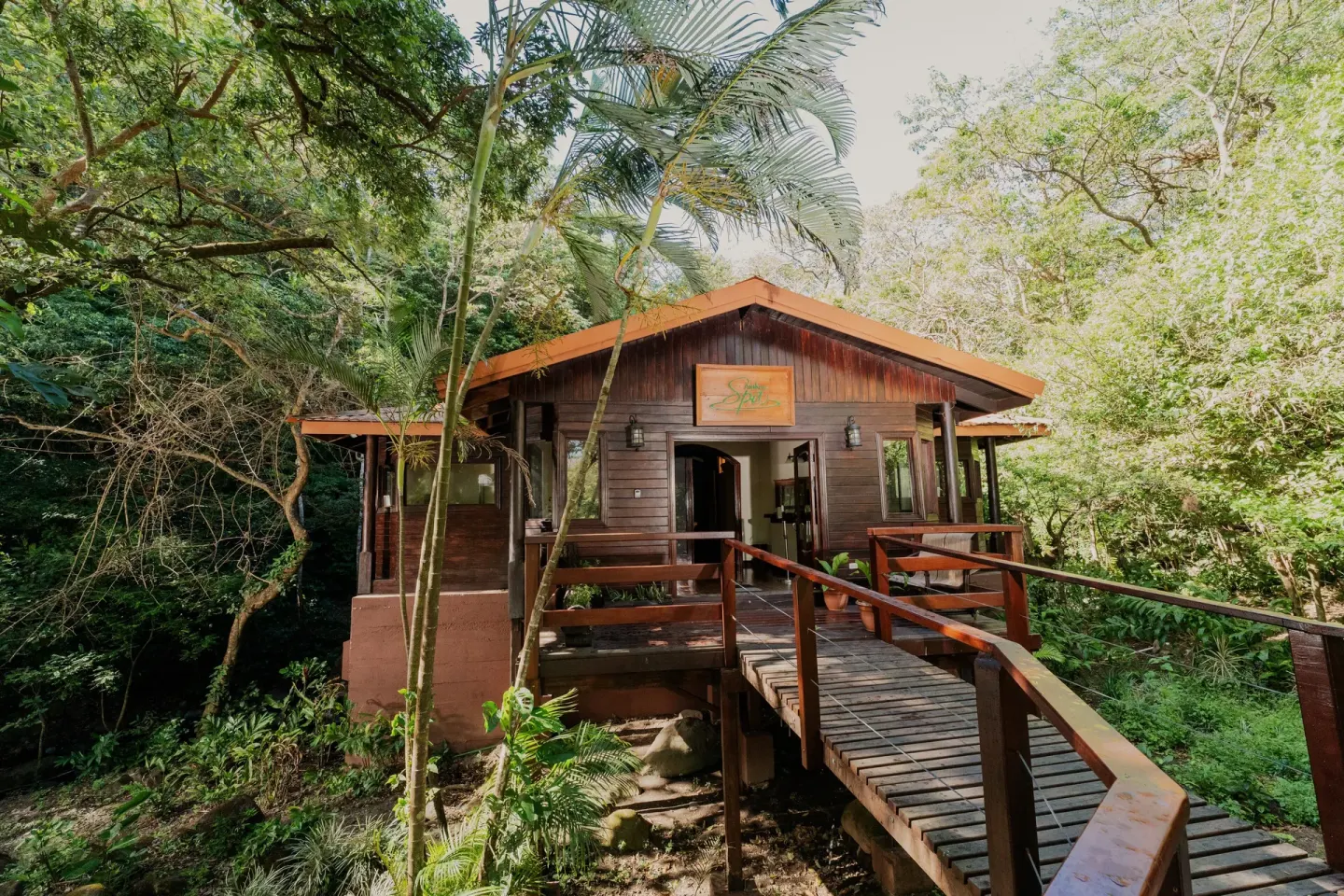 Wooden spa building reached by a forest walkway at Borinquen Thermal Resort.