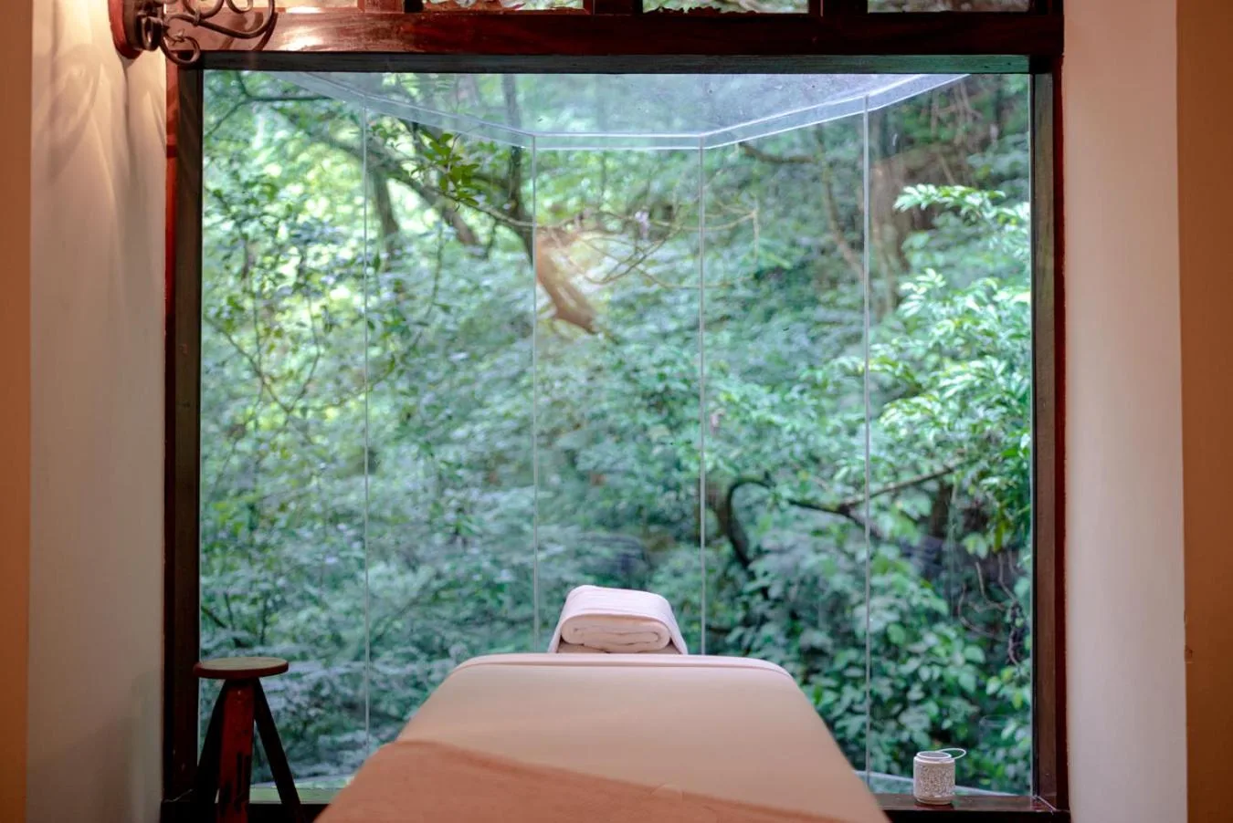 Massage table facing a floor-to-ceiling forest window at Borinquen Thermal Resort.