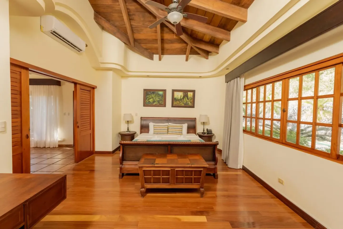 Guest room with a carved wooden bed and large windows at Borinquen Thermal Resort.