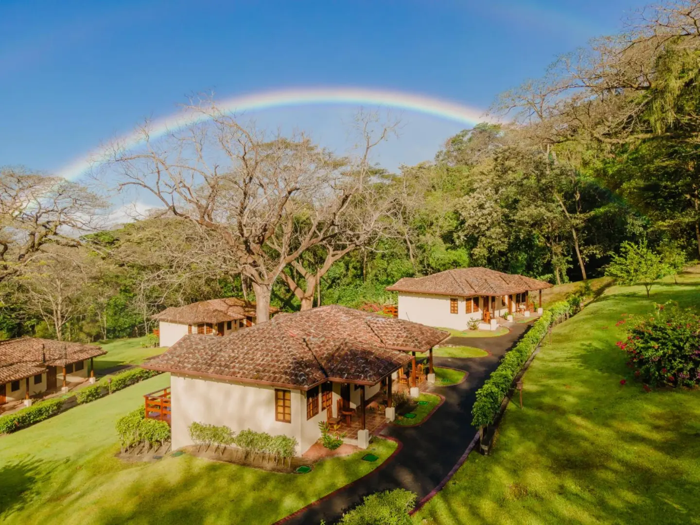 Guest villas and lawns under a rainbow at Borinquen Thermal Resort.