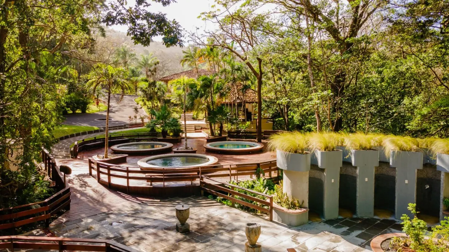 Thermal pools and wooden walkways among trees at Borinquen Thermal Resort.