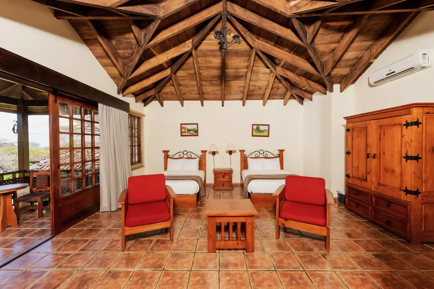 Standard Bungalow with two beds, sitting area, and balcony doors at Borinquen Thermal Resort.