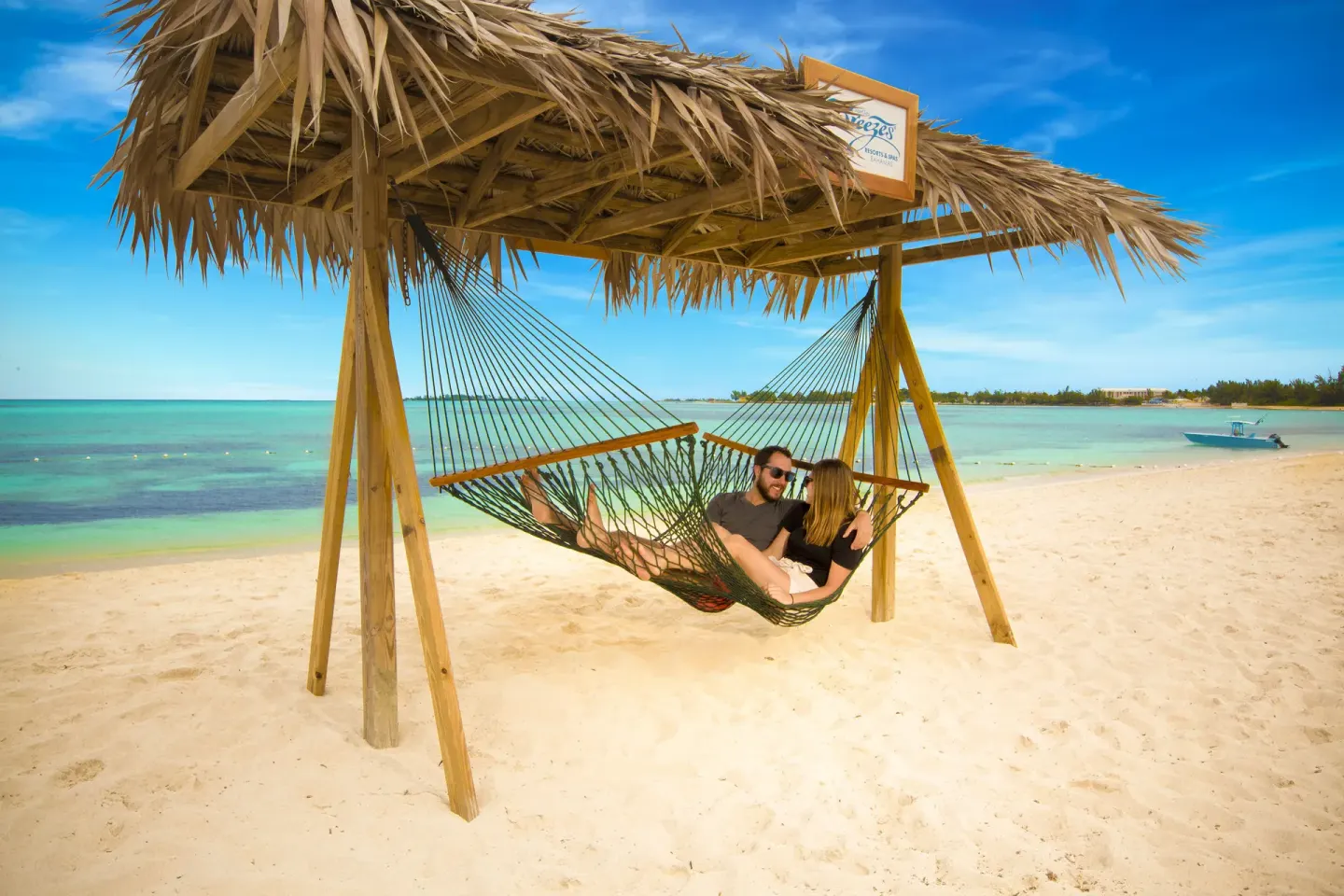 Couple relaxing in a shaded beach hammock at Breezes Resort Bahamas.