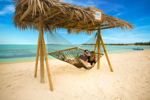 Couple relaxing in a shaded beach hammock at Breezes Resort Bahamas.