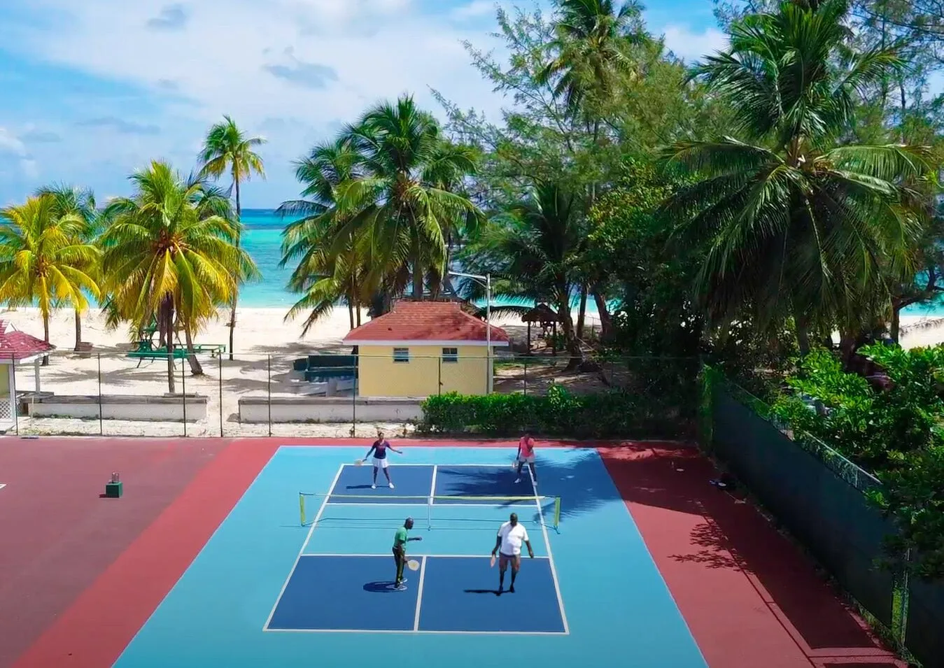 Aerial view of guests playing tennis near the beach at Breezes Resort Bahamas.