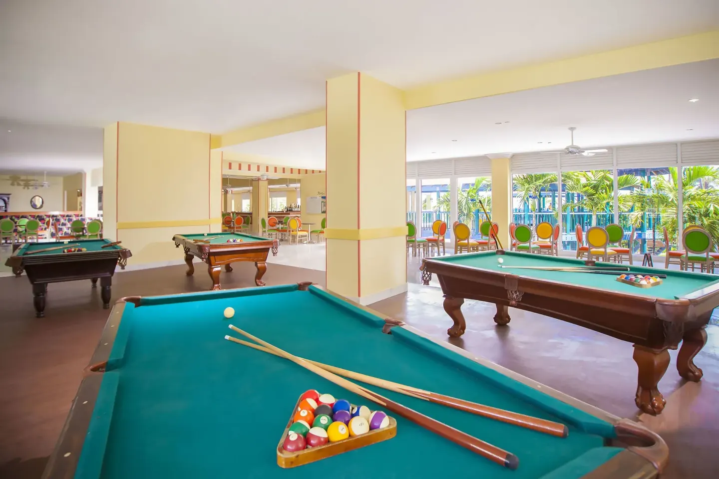Indoor game area with pool tables and colorful chairs at Breezes Resort Bahamas.