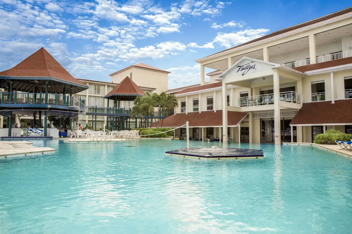 Main pool with resort buildings and a volleyball net at Breezes Resort Bahamas.