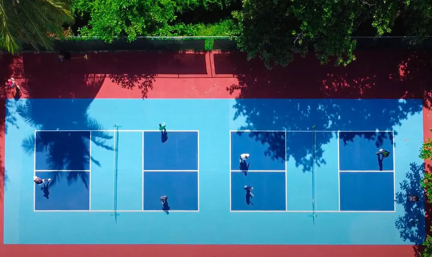 Overhead view of two blue tennis courts with players at Breezes Resort Bahamas.