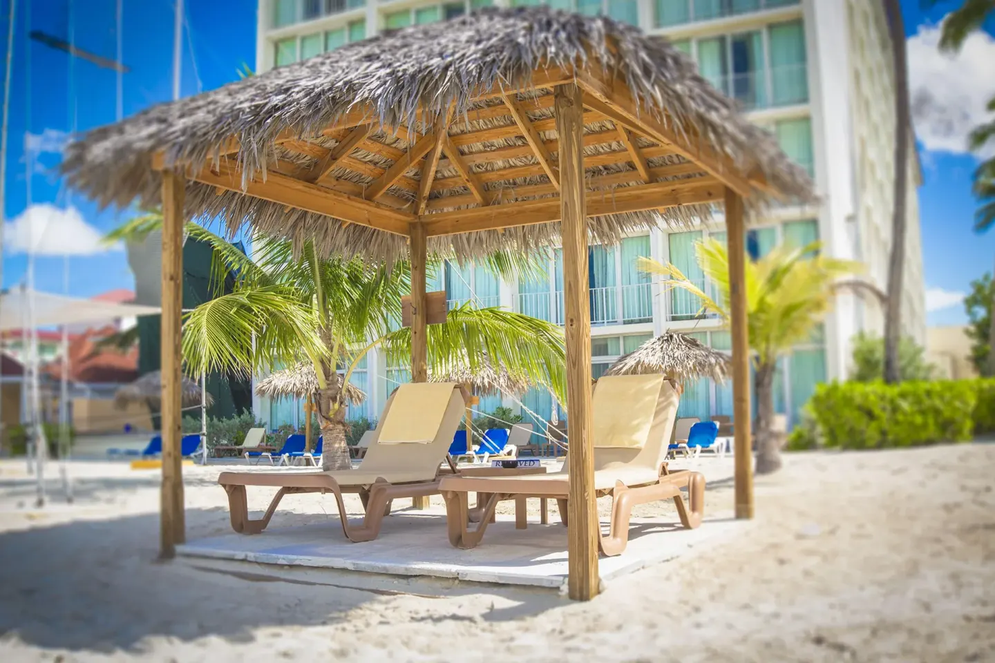 Thatched shade cabana with lounge chairs on the sand at Breezes Resort Bahamas.