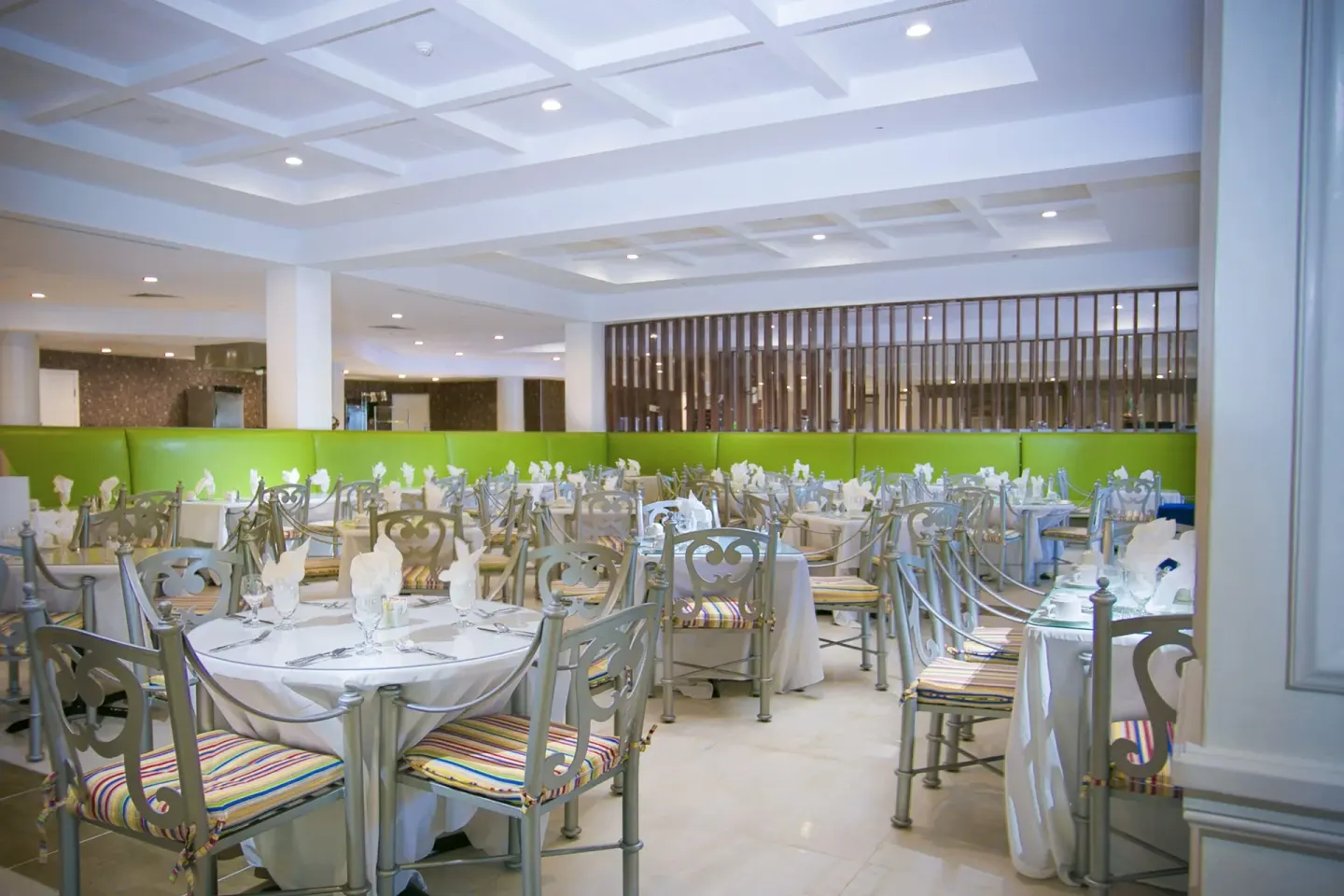 Bright dining room with round tables and silver chairs at Breezes Resort Bahamas.