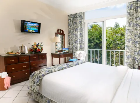 Classic Room bed near balcony doors and floral curtains at Breezes Resort Bahamas.