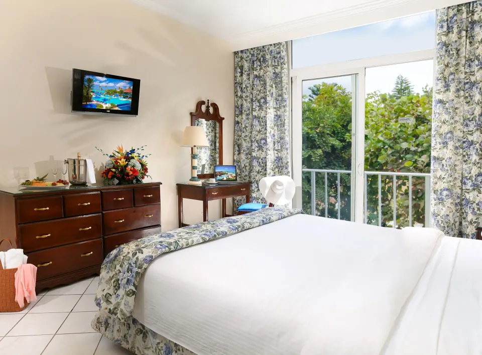 Classic Room bed near balcony doors and floral curtains at Breezes Resort Bahamas.