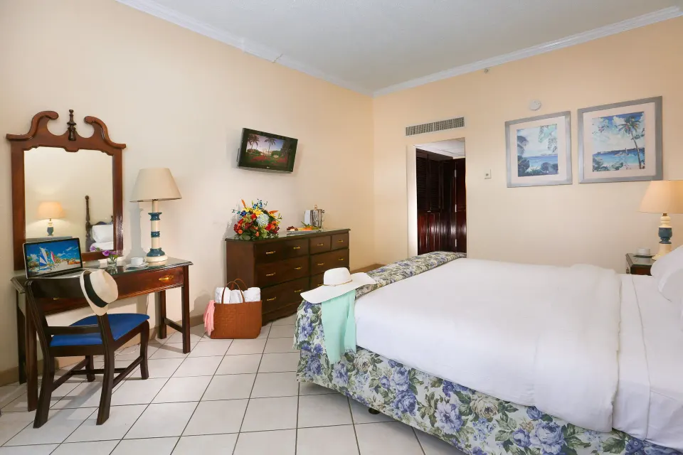 Classic Room with a bed, vanity desk, dresser, and wall art at Breezes Resort Bahamas.