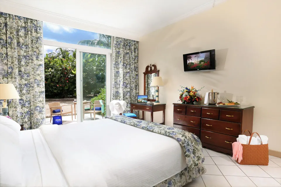 Patio Room Garden View with one bed, dresser, and patio doors at Breezes Resort Bahamas.