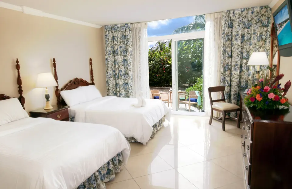 Patio Room Garden View with two beds and garden-facing glass doors at Breezes Resort Bahamas.