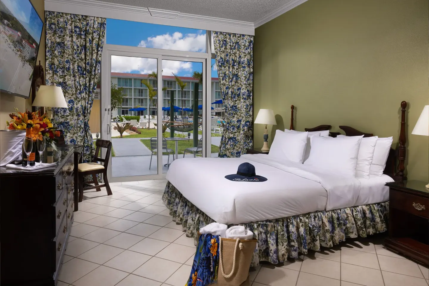 Patio Room with king bed and pool-area view through glass doors at Breezes Resort Bahamas.