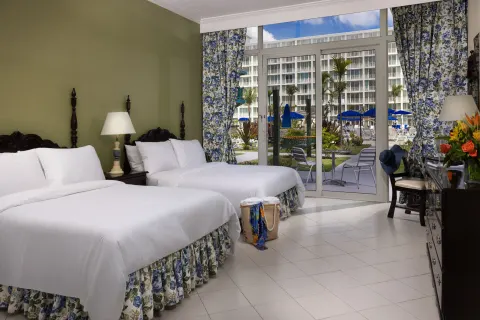 Patio Room with two beds and pool-facing glass doors at Breezes Resort Bahamas.