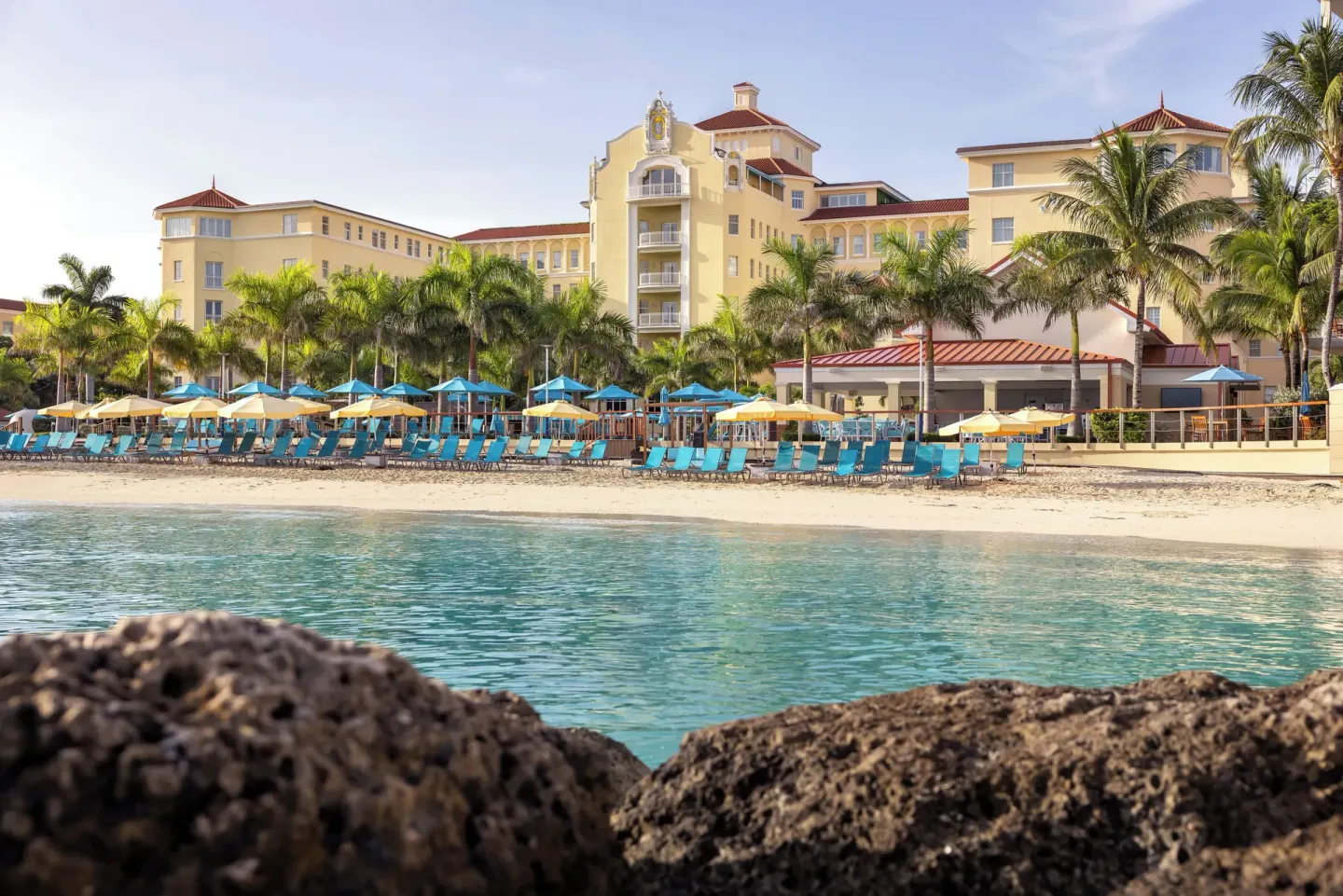 Beachfront loungers, umbrellas and yellow facade at British Colonial Nassau.
