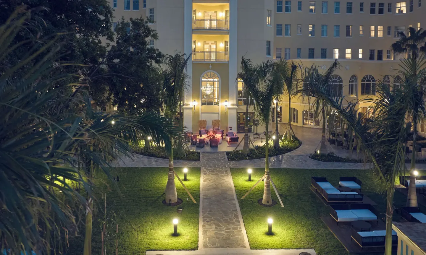 Night courtyard with lit paths, palms, and hotel balconies at British Colonial Nassau.
