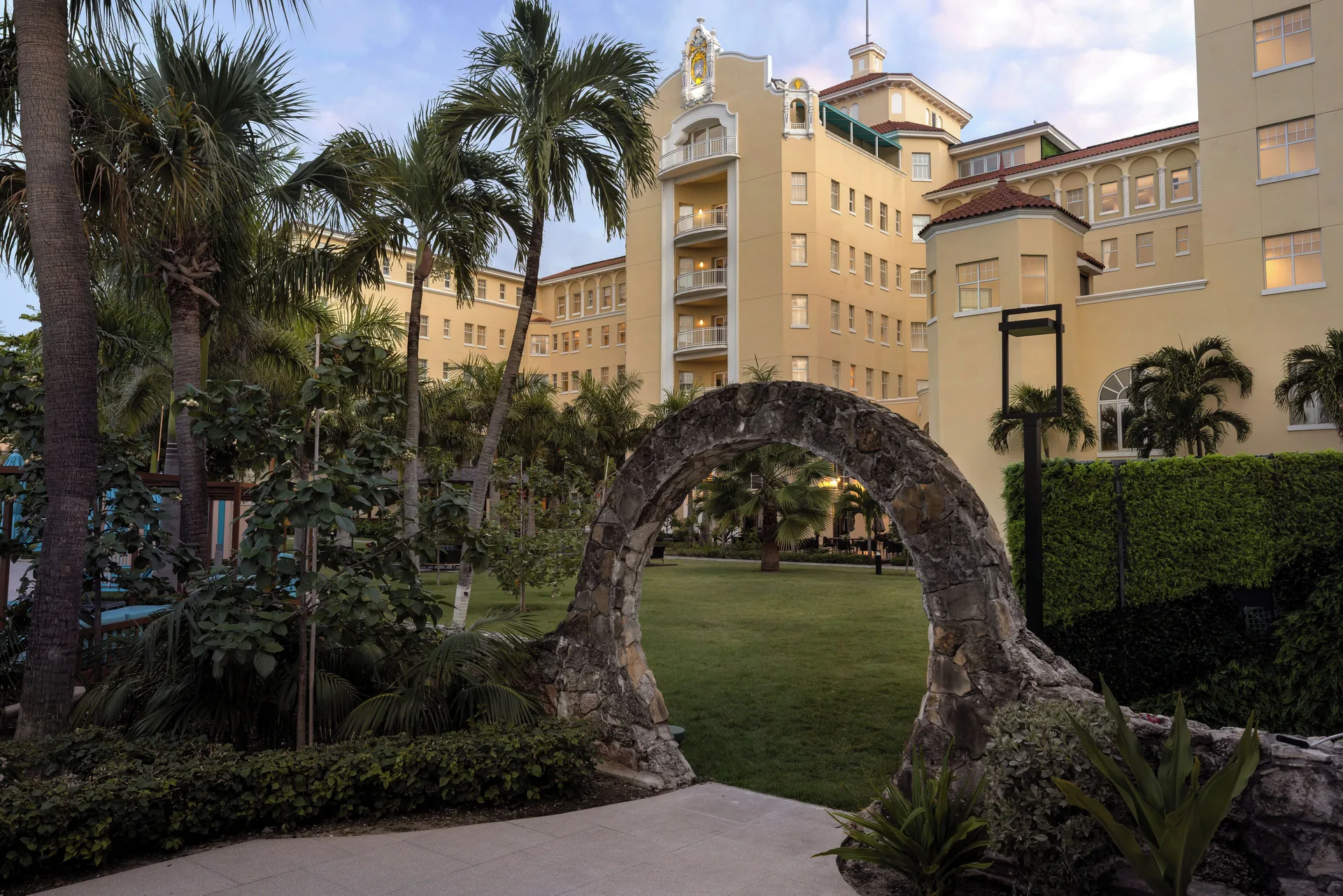 Stone garden arch, palms, and yellow hotel façade at British Colonial Nassau.