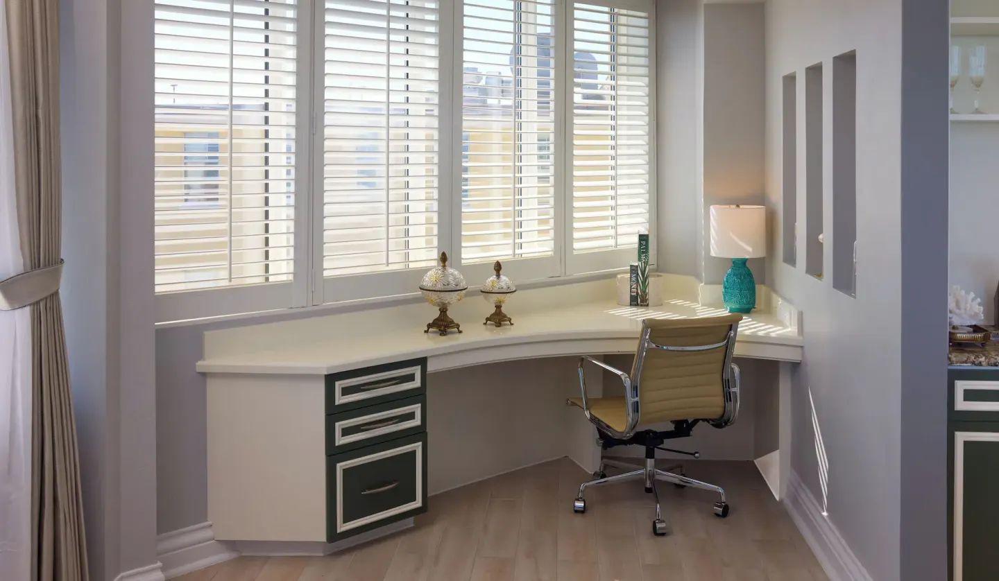 Guest room work desk with white shutters, rolling chair, and turquoise lamp at British Colonial Nassau.