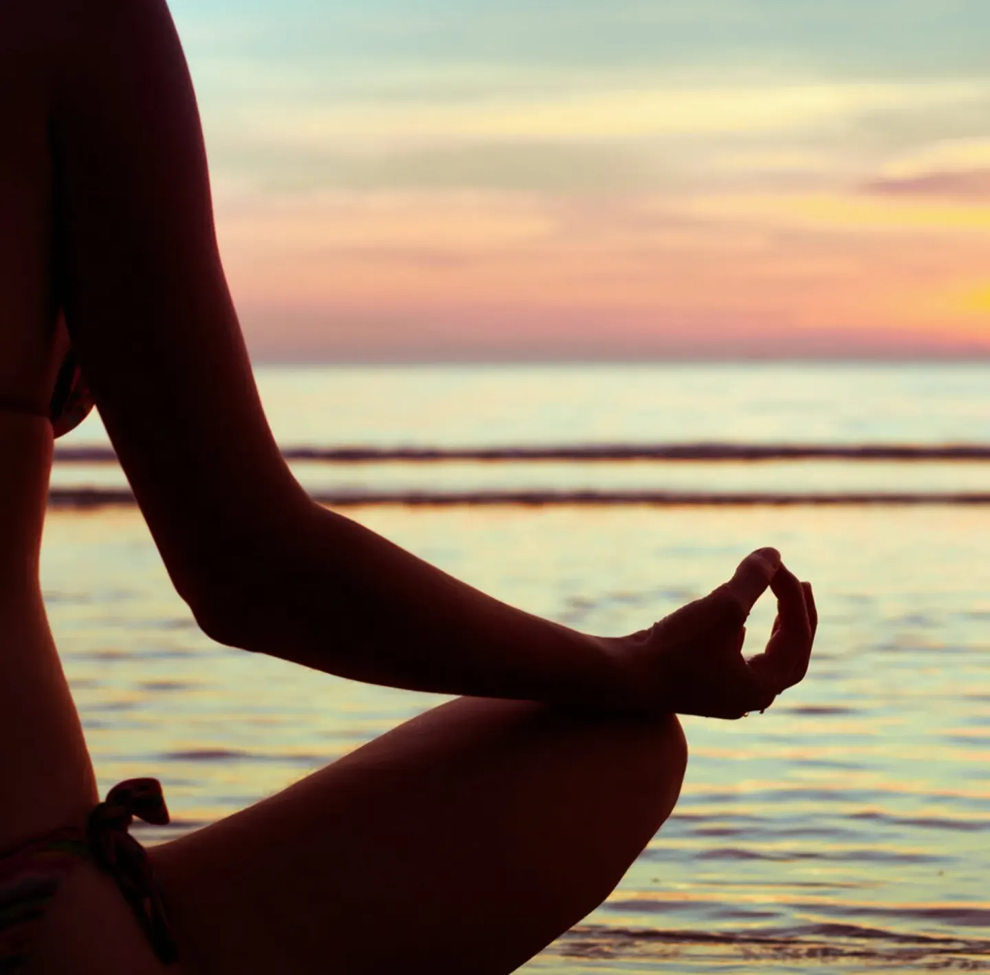 Person meditating by the ocean at sunset near British Colonial Nassau.