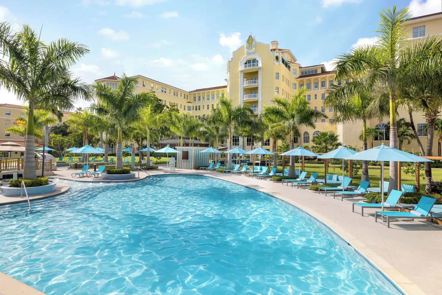 Resort pool with palm trees and blue umbrellas at British Colonial Nassau.