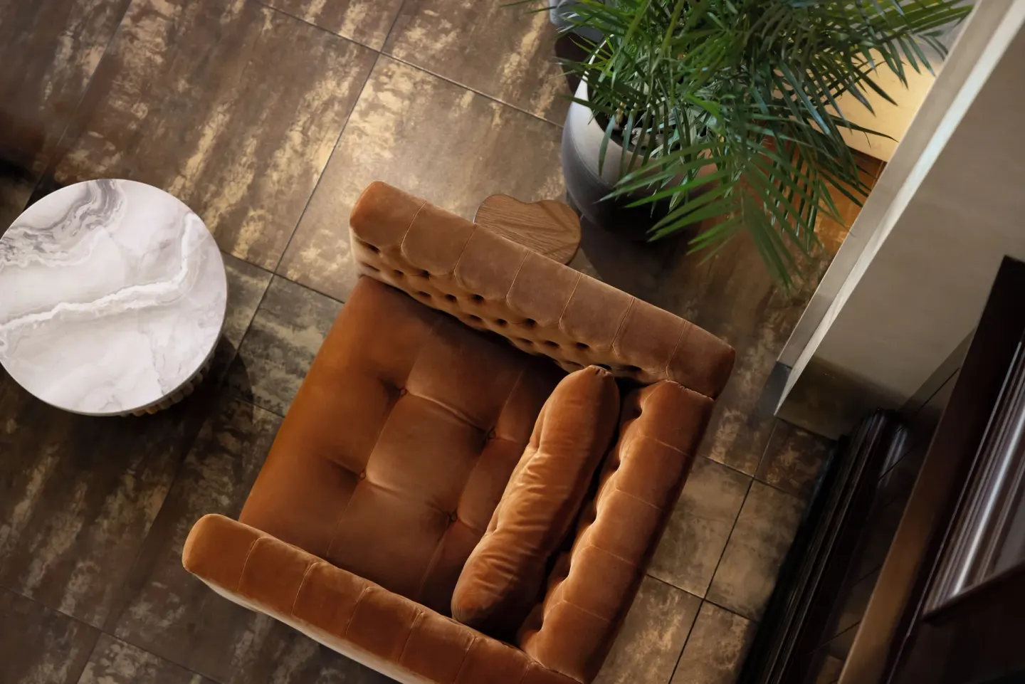 Overhead view of a tufted lounge chair, side table, and potted palm at British Colonial Nassau.