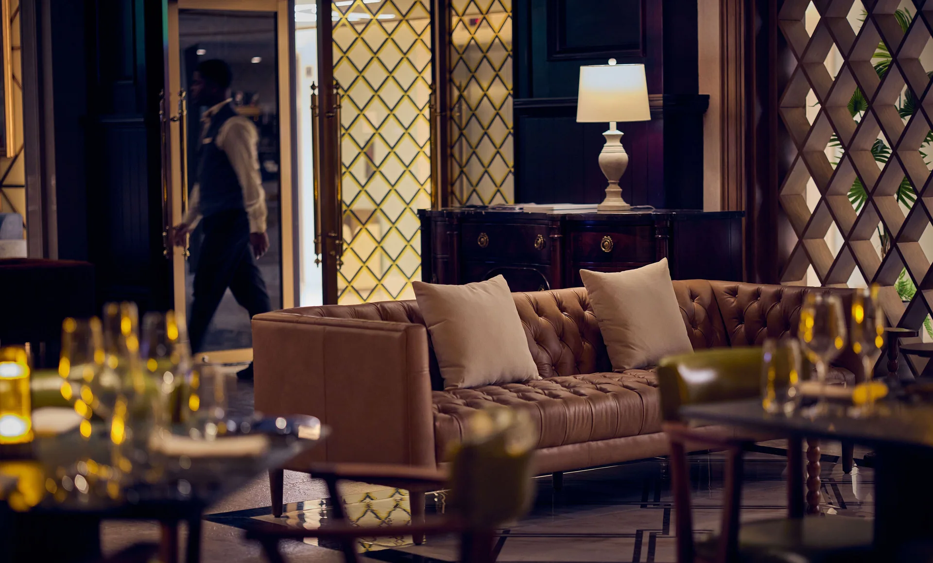 Dim lounge with leather sofa, lamp, glassware, and lattice doors at British Colonial Nassau.