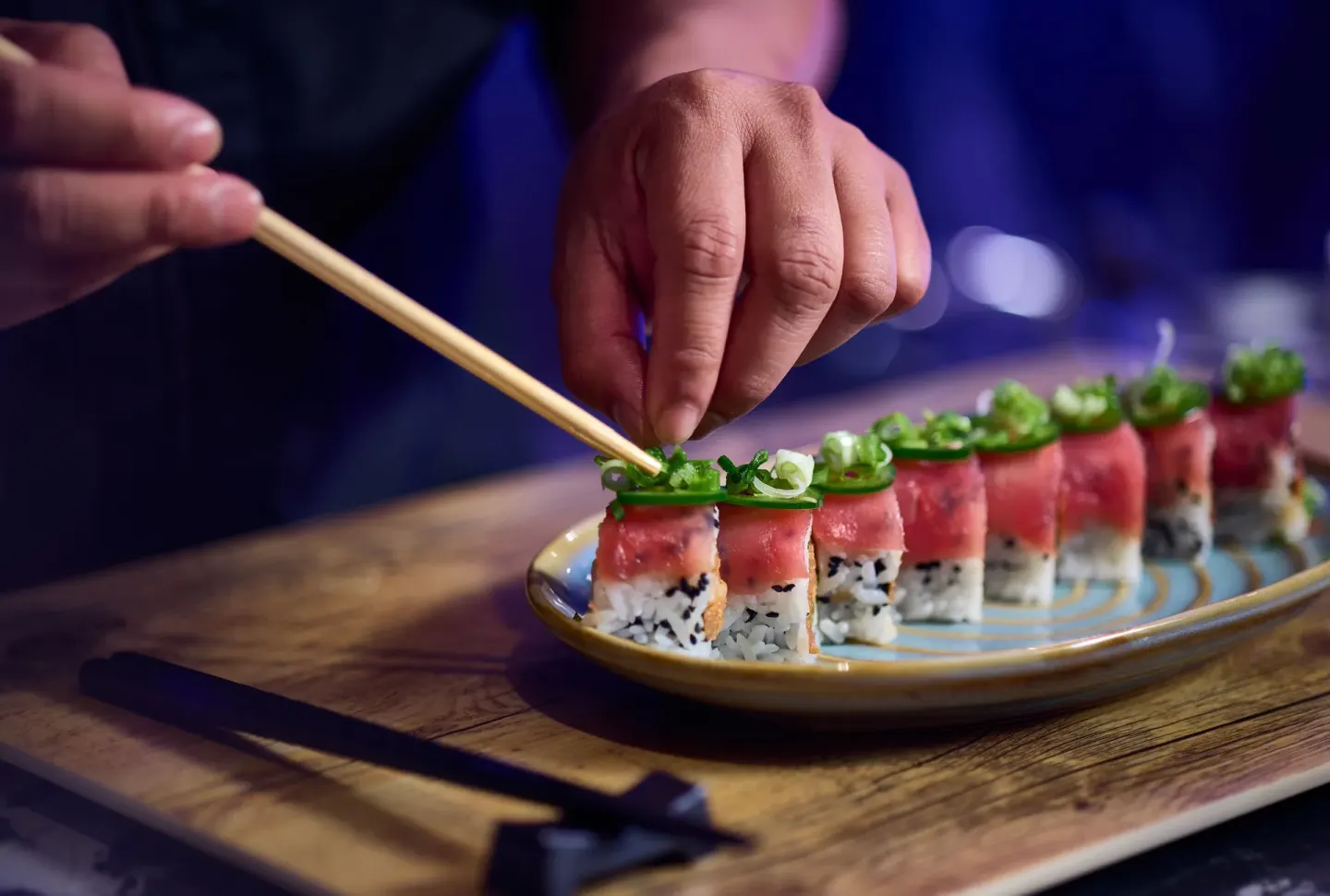 Chef garnishing sushi rolls with chopsticks at British Colonial Nassau.
