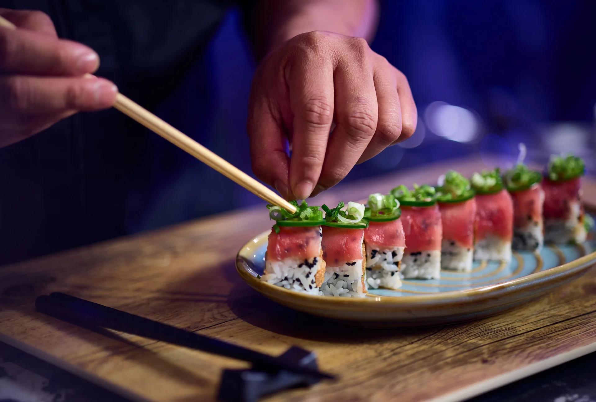 Chef garnishing sushi rolls with chopsticks at British Colonial Nassau.