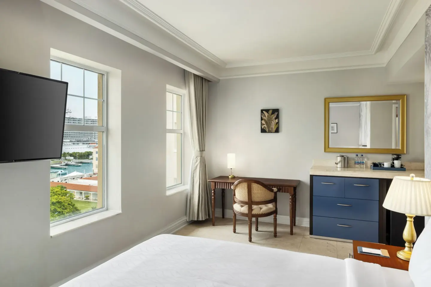 Ocean View room with bed, TV, desk, vanity, and cruise ship view at British Colonial Nassau.