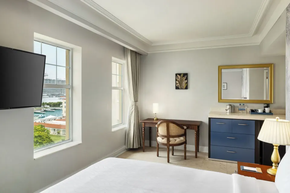 Ocean View room with bed, TV, desk, vanity, and cruise ship view at British Colonial Nassau.
