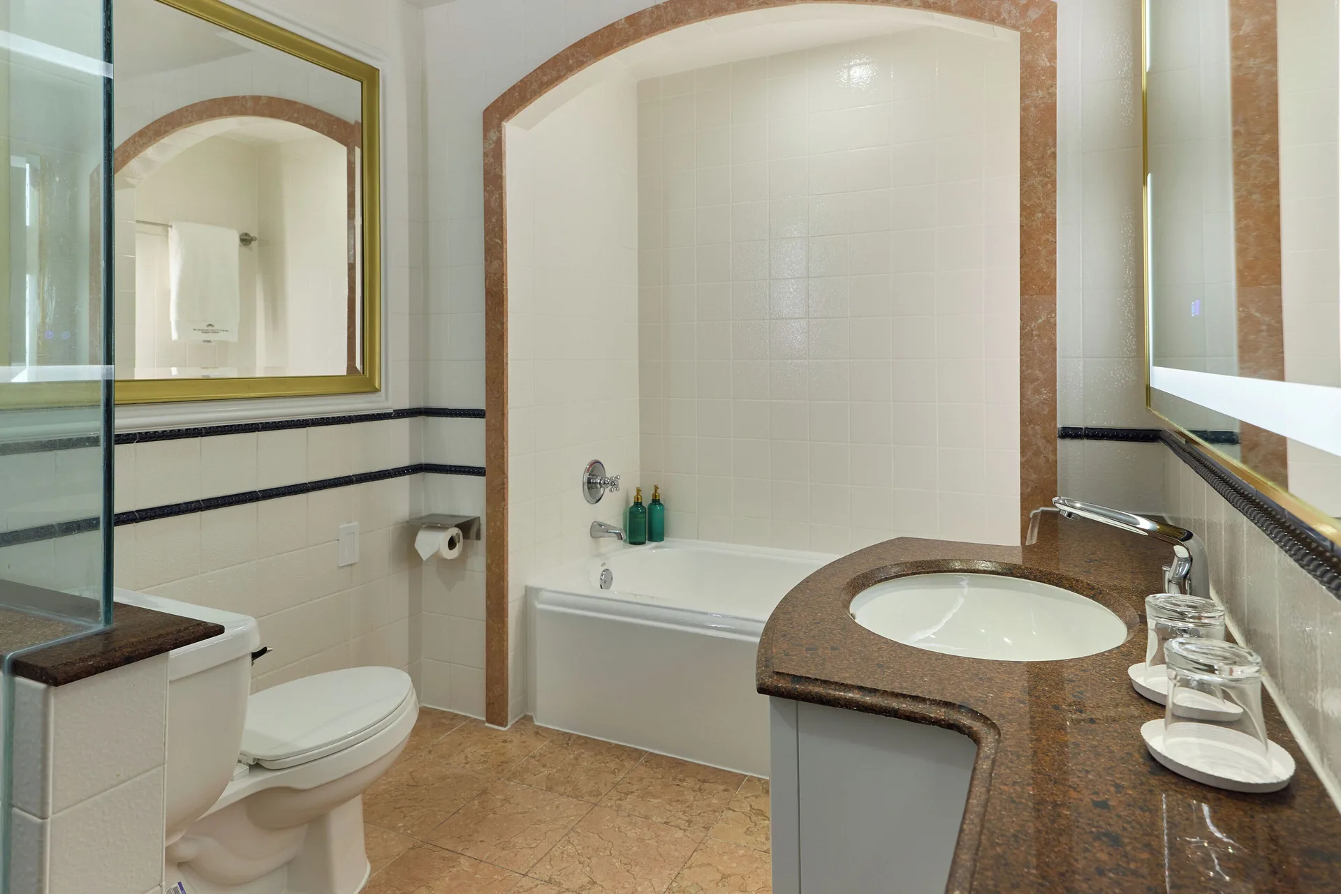 Standard Room bathroom with tub, vanity, toilet, and mirror at British Colonial Nassau.