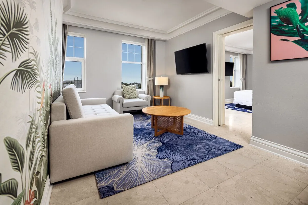 Standard Suite sitting room with sofa, armchair, coffee table, and bedroom doorway at British Colonial Nassau.