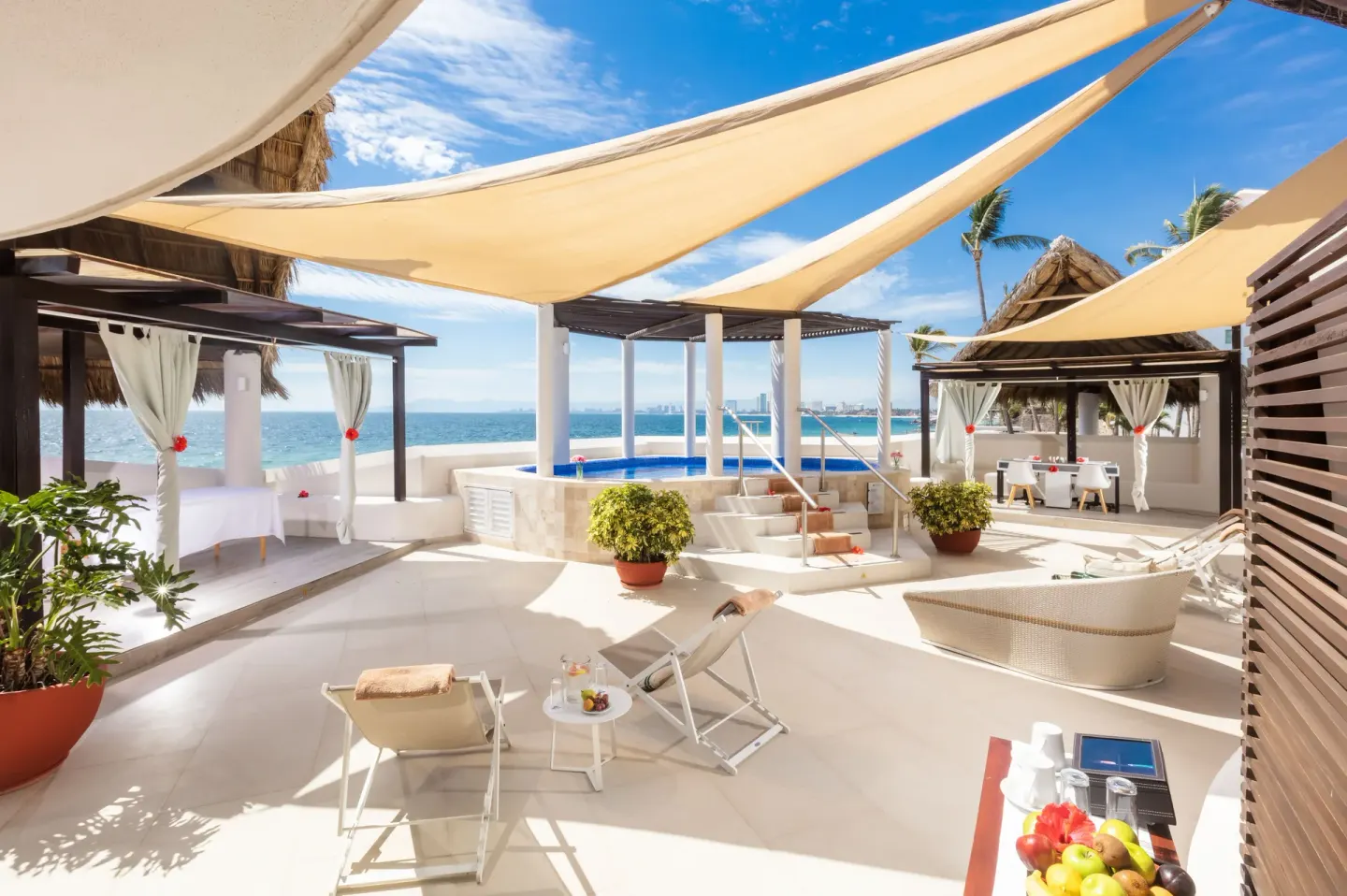 Spa deck with loungers, cabanas, fruit tray, and ocean view at Buenaventura Grand Hotel & Great Moments.