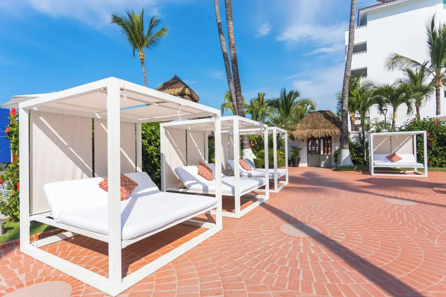 White daybeds on a palm-lined terrace at Buenaventura Grand Hotel & Great Moments.