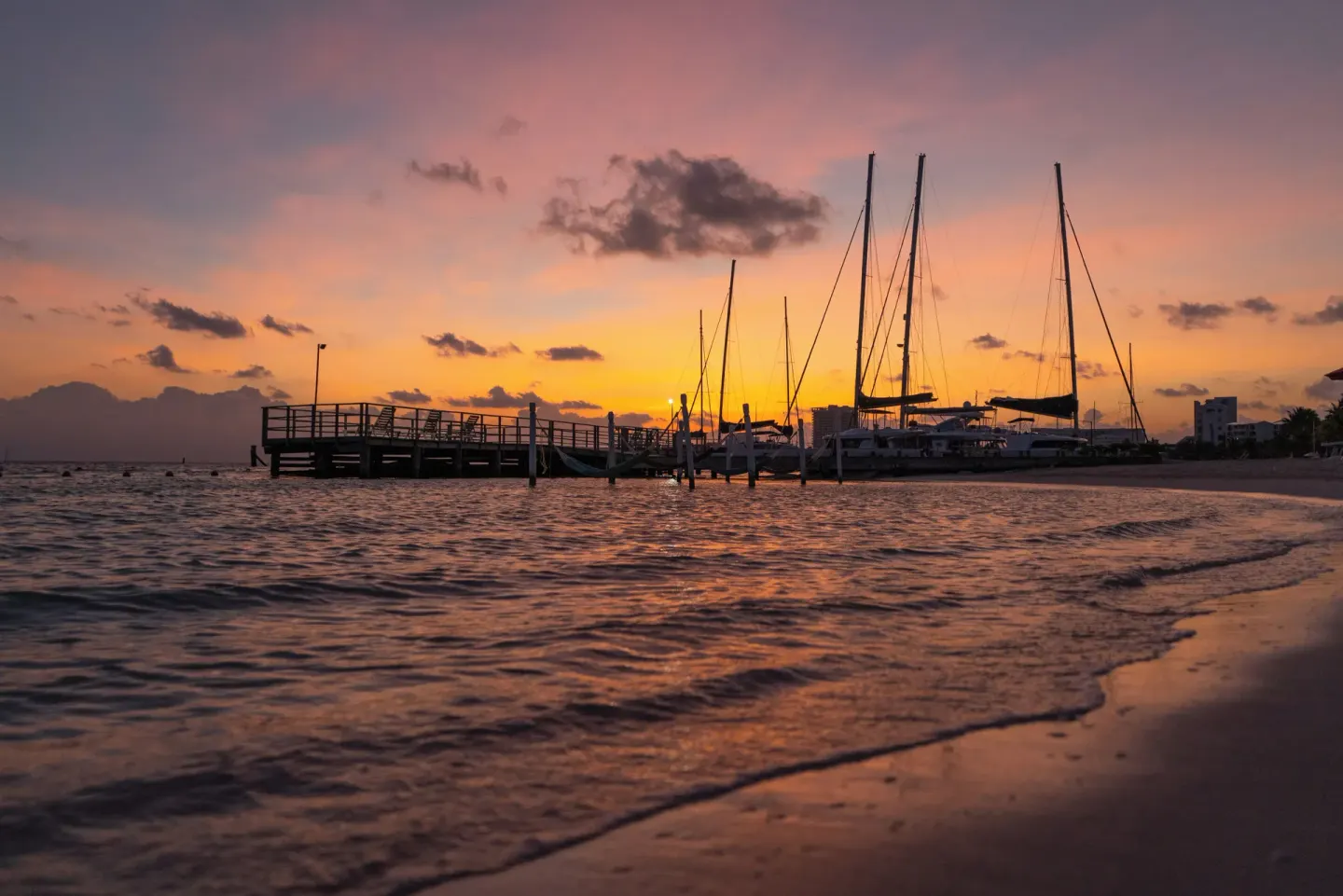 Sunset over the beach pier and sailboats at Cancun Bay Hotel.