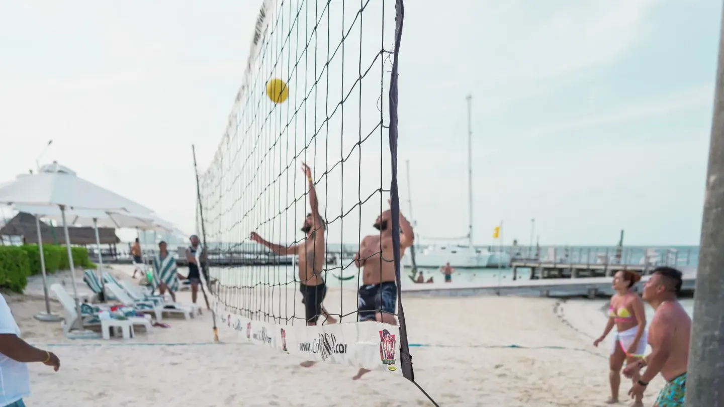 Guests play beach volleyball beside the water at Cancun Bay Hotel.