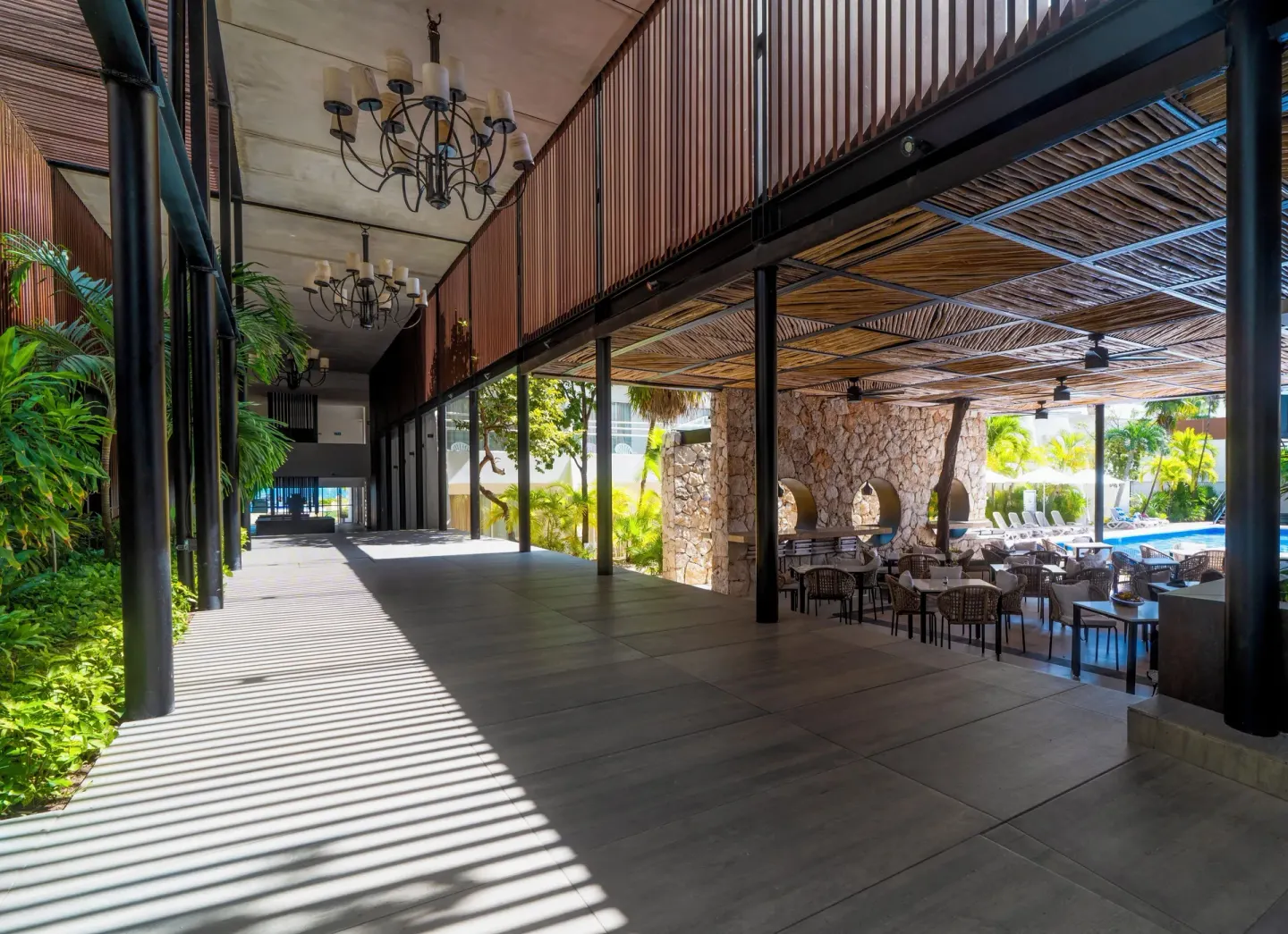 Covered walkway beside poolside seating and tropical plants at Cancun Bay Hotel.
