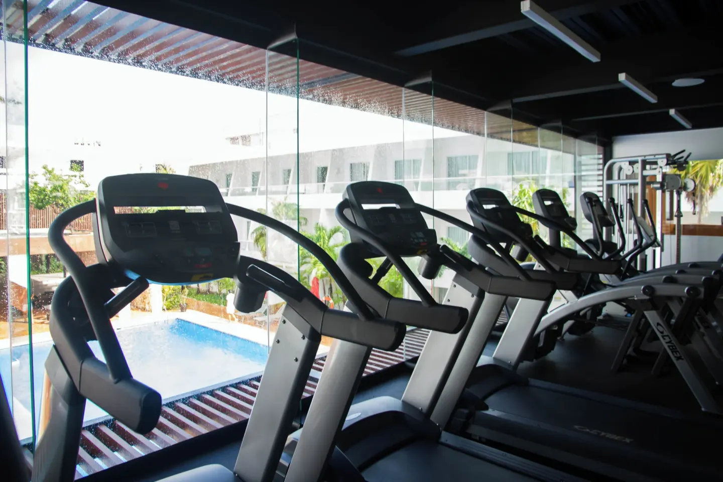 Cardio machines overlook the pool through glass at Cancun Bay Hotel.